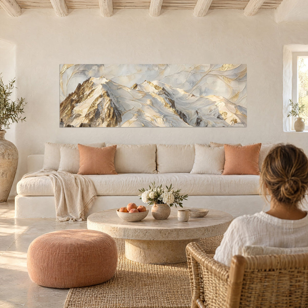 Gemälde Schneegipfel mit goldenen Adern auf Creme und Perlgrau, Frau von hinten, über einem Sofa in einem hellen Wohnzimmer