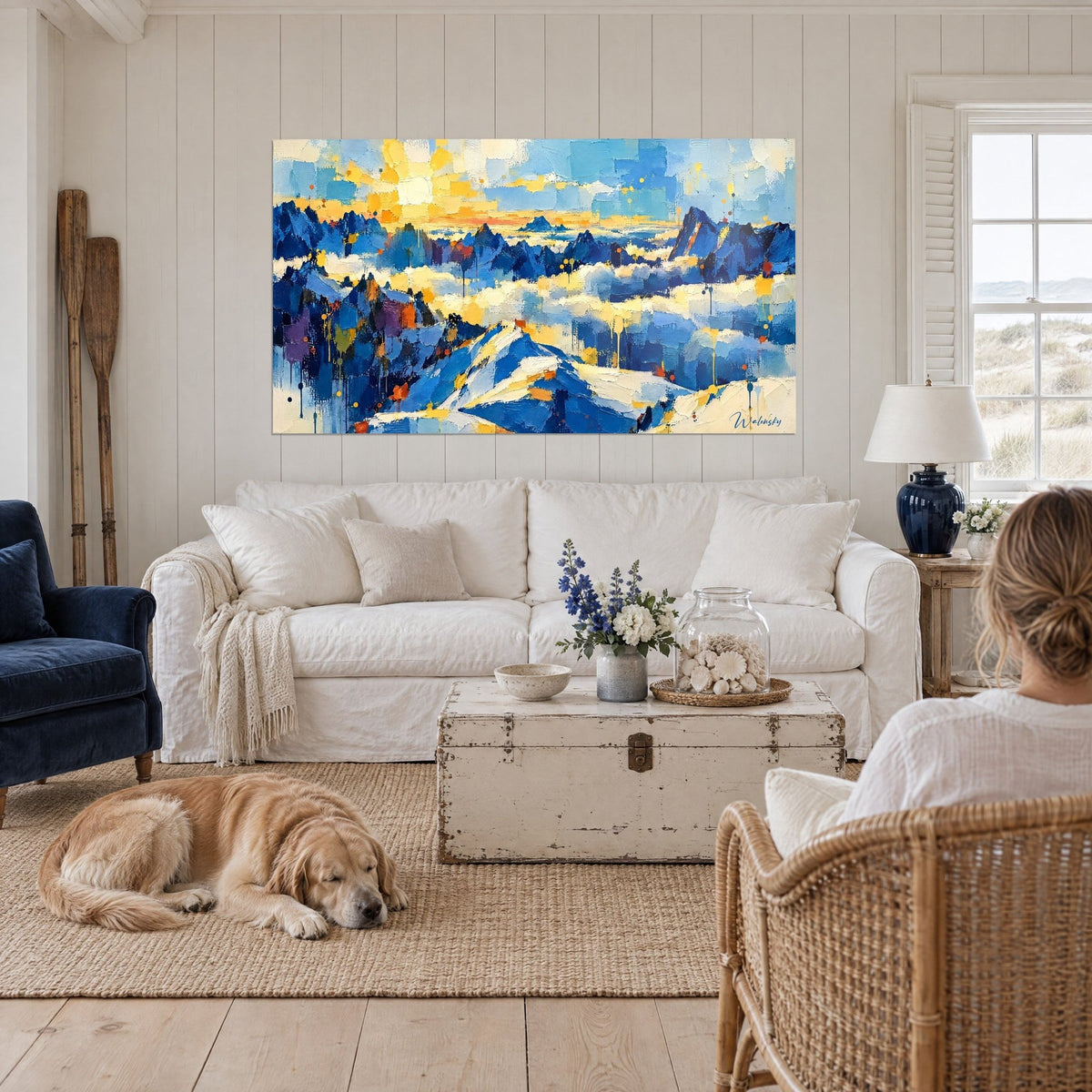 Wall art cobalt blue peaks rising from a sea of golden yellow clouds, above a sofa in a bright living room