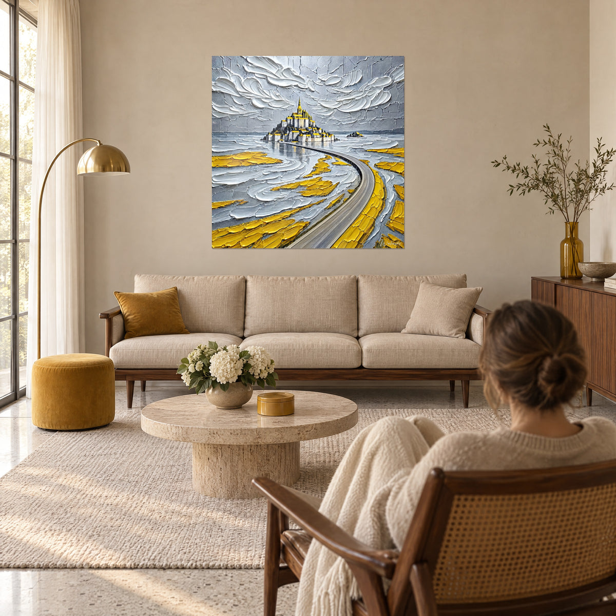 Schilderij Mont-Saint-Michel in dikke verf, gouden abdij boven grijze en gele zandvlakten, boven een bank in een lichte woonkamer