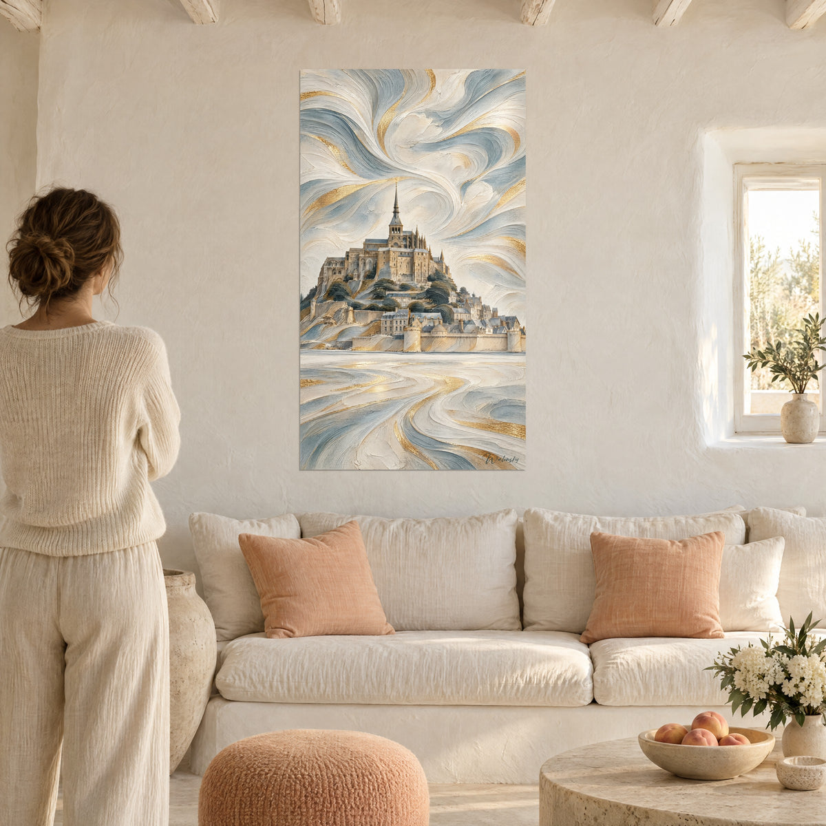 Wall art ivory abbey with golden spire on its rock, blue-grey swirls, woman seen from behind, above a sofa in a bright living room