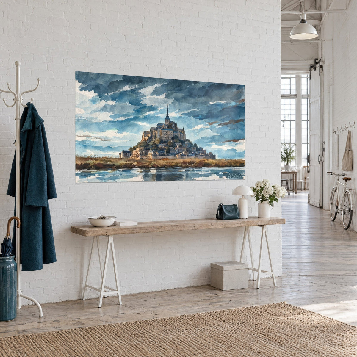 Obraz Mont-Saint-Michel w akwareli, ciemna iglica, stalowoniebieskie chmury i odbicia wody, na białej ścianie wejściowej loftu