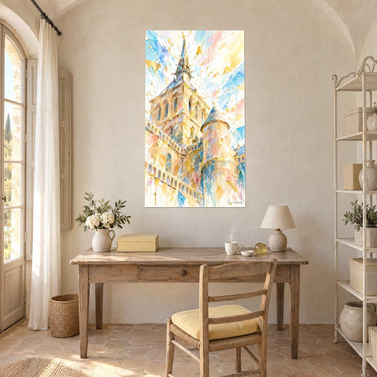 Cuadro torre gótica en acuarela, ocre dorado y azul cielo, sobre un escritorio de madera clara con lámpara y flores blancas