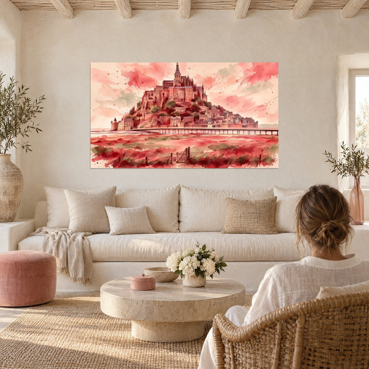 Quadro di abbazia con guglie gotiche in acquerello corallo e salvia, donna di spalle, sopra un divano in un soggiorno luminoso