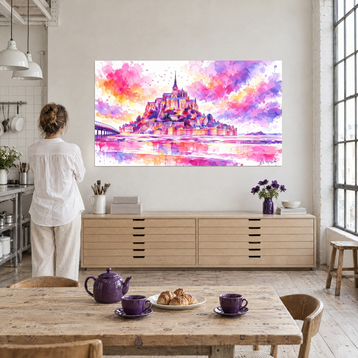 Schilderij heilig eiland met okerkleurige daken, orchidee- en abrikooskleurige lucht, een vrouw van achteren op de voorgrond, kunstenaarsloft met grote ramen