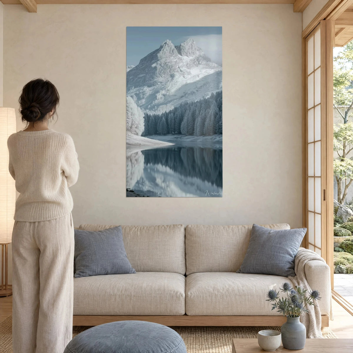 Tableau sommet enneigé en double pic, reflété dans un lac bleu acier, femme de dos, au-dessus d'un canapé dans un salon lumineux