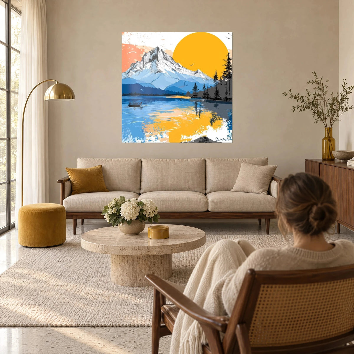 Wall art snow-capped peak under a large yellow sun, cobalt blue lake with saffron reflections, woman seen from behind, above a sofa in a bright living room