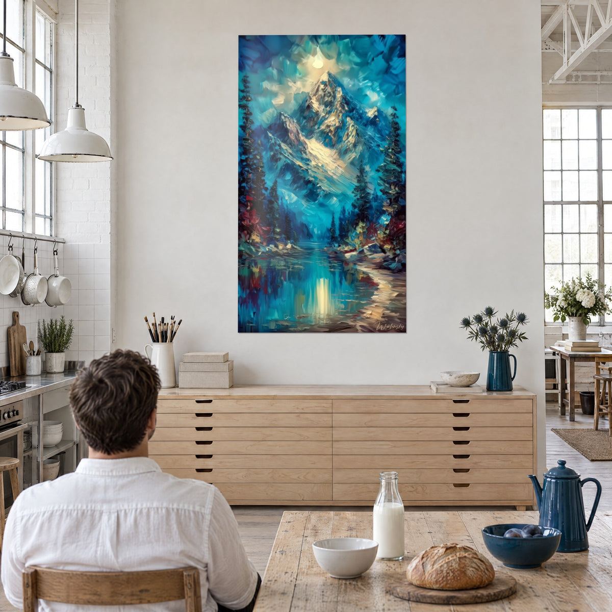Cuadro macizo rocoso iluminado por la luna, abetos verdes y toques rojos, lago azul profundo, frente a una mesa de cocina de madera clara