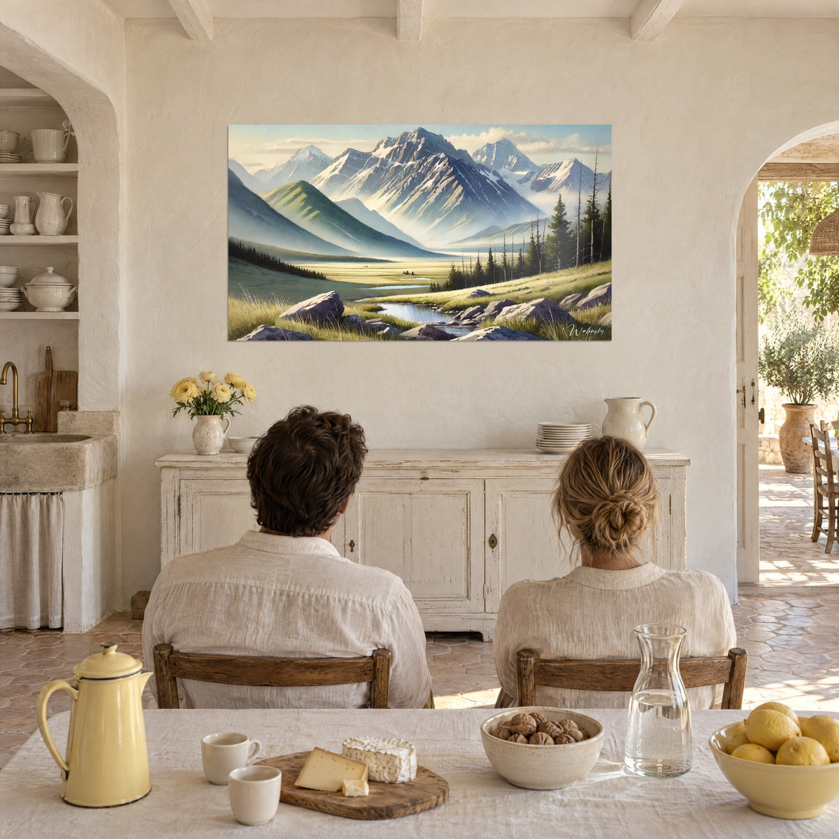Quadro di una catena montuosa ad acquerello, versanti grigio-azzurri e prato dorato, laghetto scintillante, di fronte a una coppia seduta a tavola di spalle
