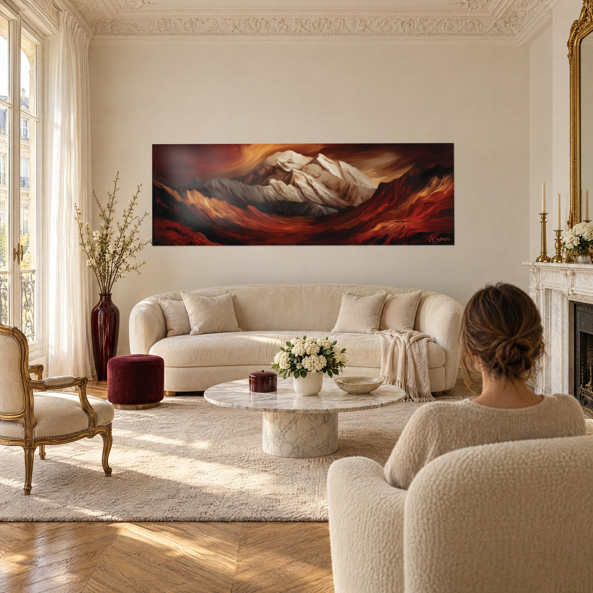 Tableau massif alpin blanc et rouge brique, ciel orangé en volutes, au-dessus d'un canapé dans un salon lumineux
