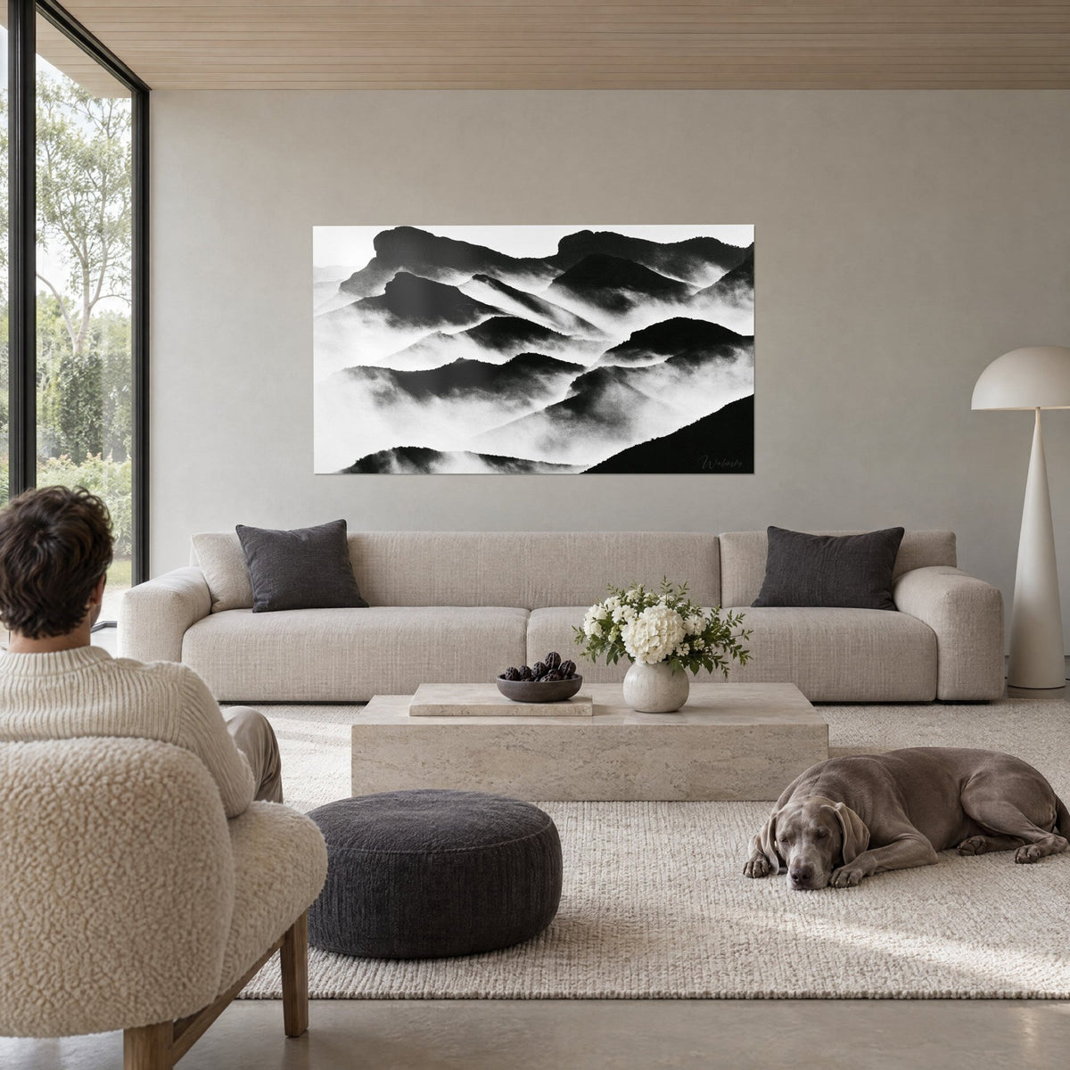 Tableau sommets noirs dans la brume, strates en noir et blanc, deux personnes de dos, au-dessus d'un canapé dans un salon lumineux