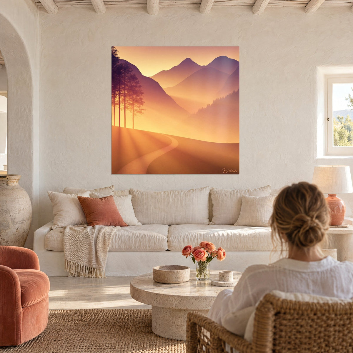 Schilderij gouden slingerpad tussen mauve bergruggen en tegenlicht dennen, vrouw van achteren boven een bank in een lichte woonkamer