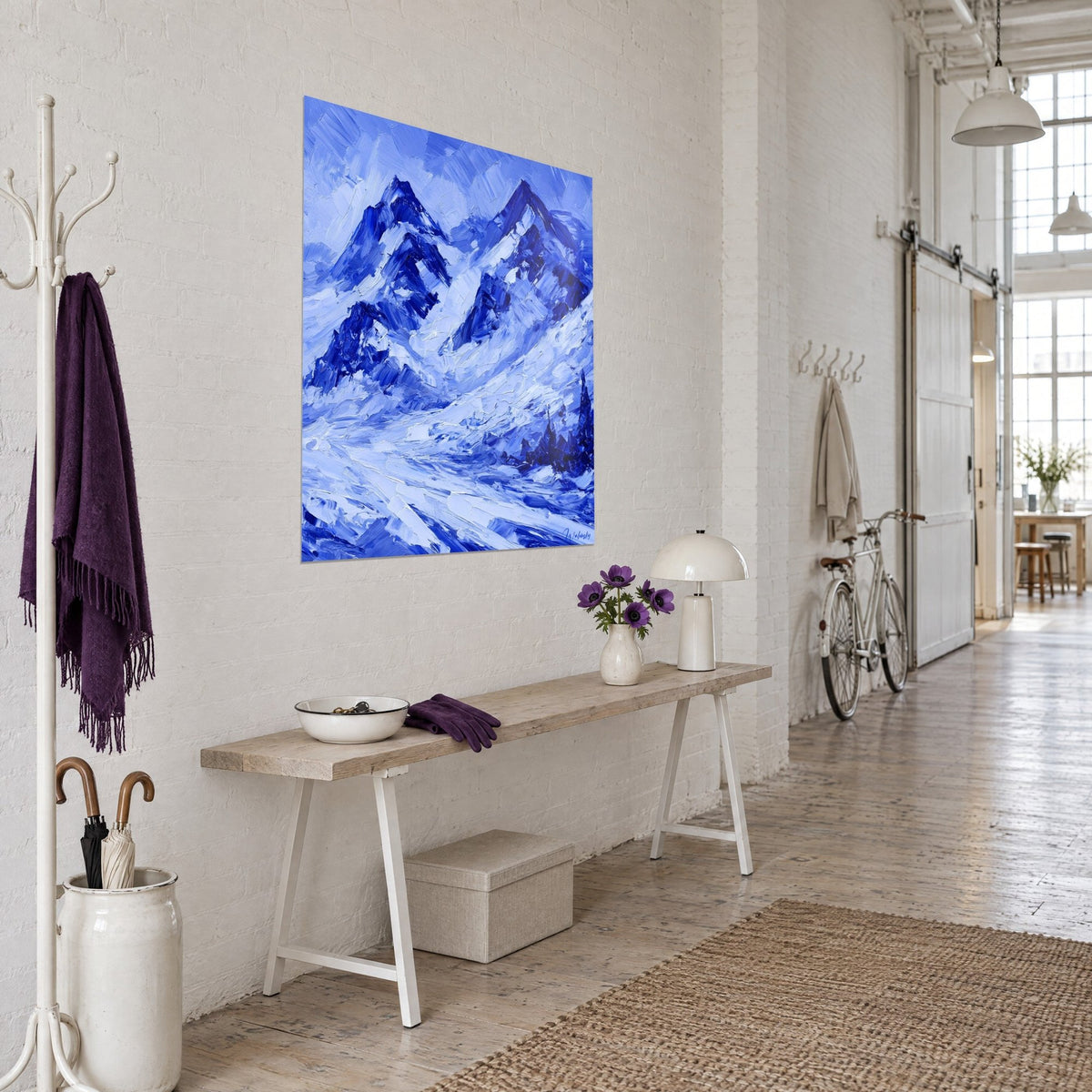 Massive alpine wall art in heavy impasto, indigo ridges and white snowfields, three-quarter view on the white wall of an artist's loft