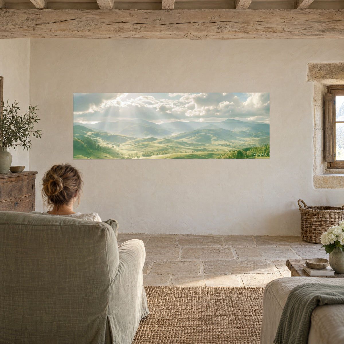Tableau vallons verdoyants et brume bleutée, rayons de soleil perçant les nuages blancs, personne de dos, salon en pierre claire