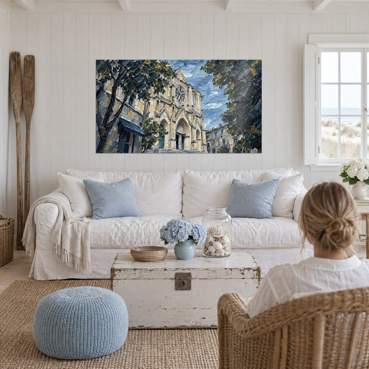 Tableau façade gothique ocre sous un ciel bleu empâté, rosace en pierre, personne de dos au-dessus d'un canapé dans un salon lumineux
