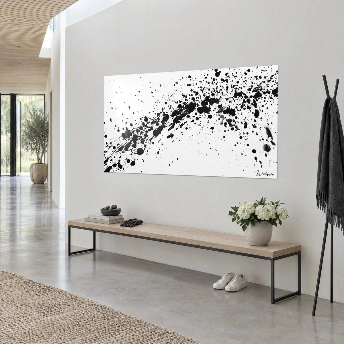 Wall art with black droplets on pure white, curved speckled trajectory, three-quarter view, wooden bench and white flowers, light grey wall