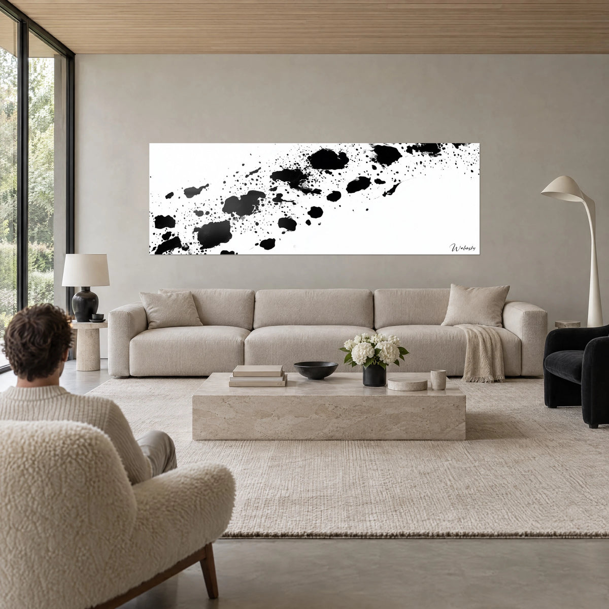 Gemälde mit diagonalen schwarzen Tintenspritzern auf weißem Grund, zwei Personen von hinten, über einem Sofa in einem hellen Wohnzimmer