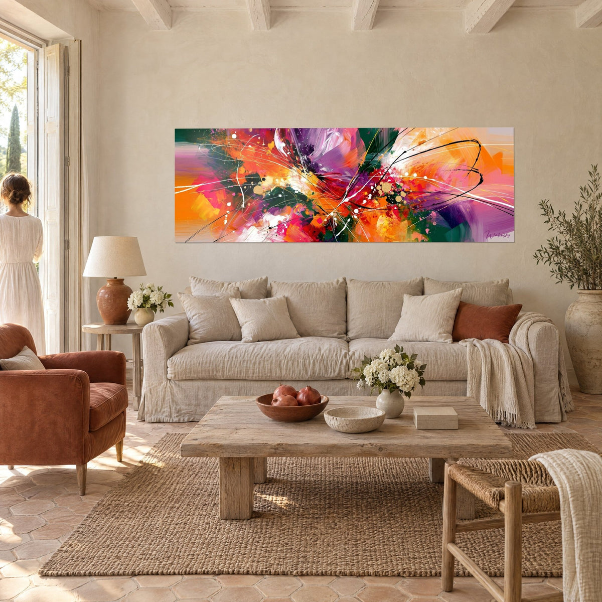 Cuadro de gestos pictóricos naranjas y violetas, trazos negros y gotas doradas, sobre un sofá en un salón luminoso
