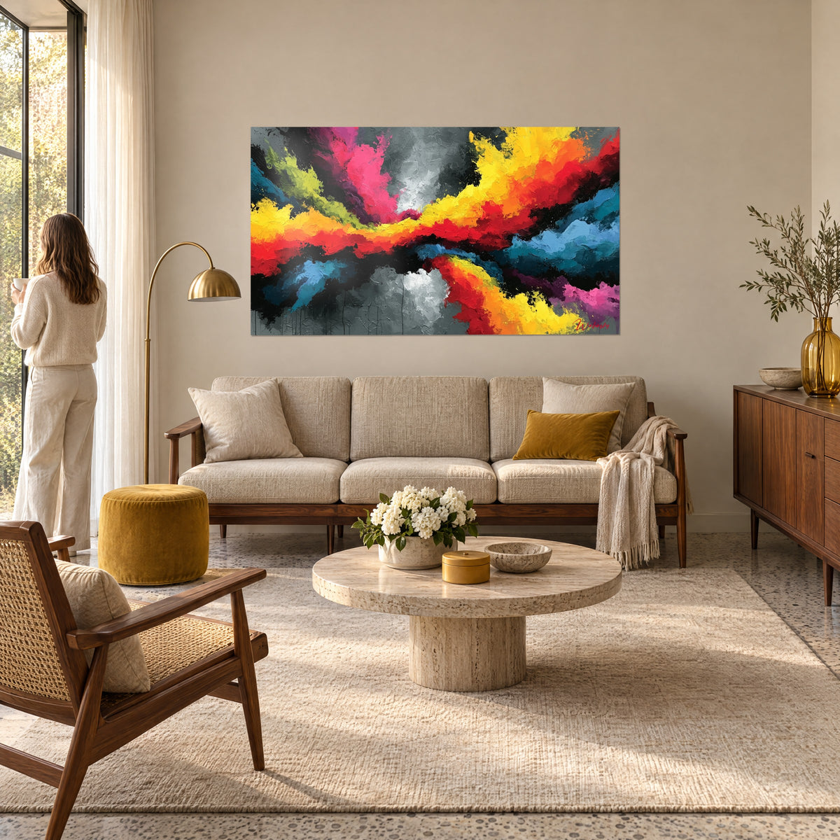 Quadro esplosione di fiamme gialle e rosa su fondo antracite, donna di spalle, sopra un divano in un soggiorno luminoso