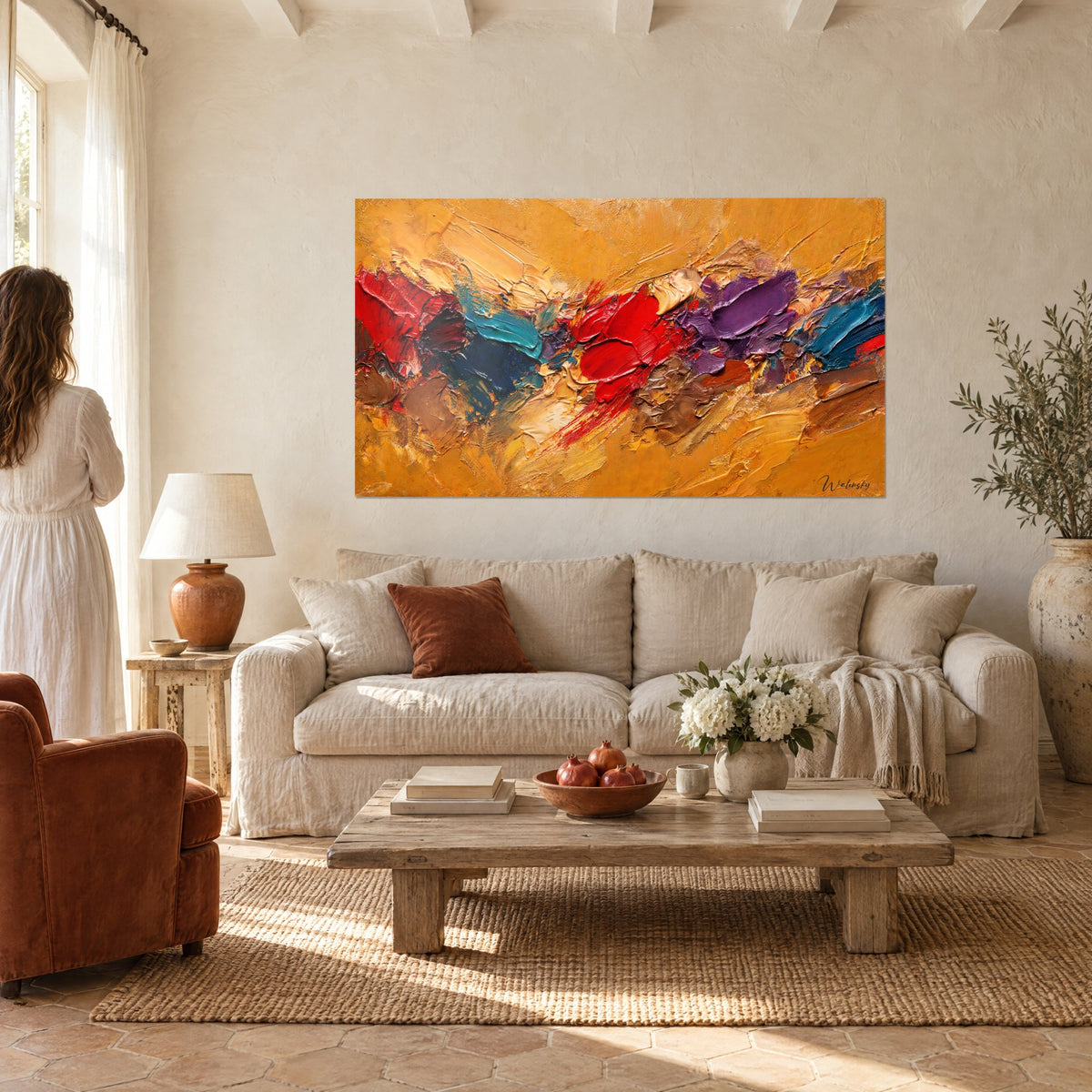 Tableau coulée dorée aux empâtements rouge vif et bleu canard, accroché sur un mur blanc, au-dessus d'un canapé dans un salon lumineux