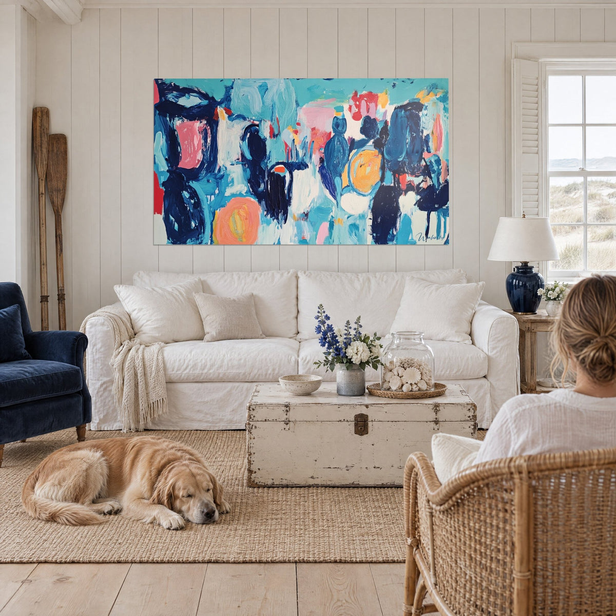 Gemälde abstrakt mit marineblauen und lachsrosa Flecken, orangefarbene Sonne unten, über einem Sofa in einem hellen Wohnzimmer