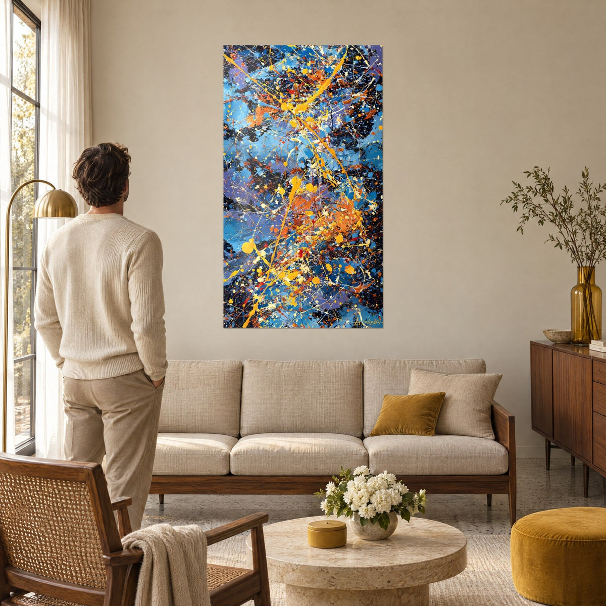 Wall art sky blue and vivid orange paint splatters, yellow drips on a dark background, above a sofa in a bright living room