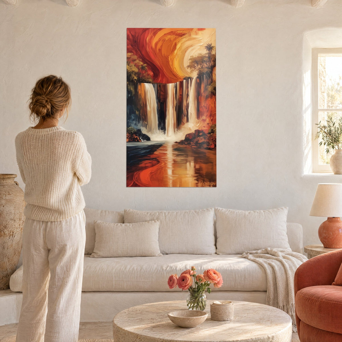 Tableau chute d'eau en cascade, ciel orange et rouge tourbillonnant, vue de dos d'une femme, au-dessus d'un canapé dans un salon lumineux