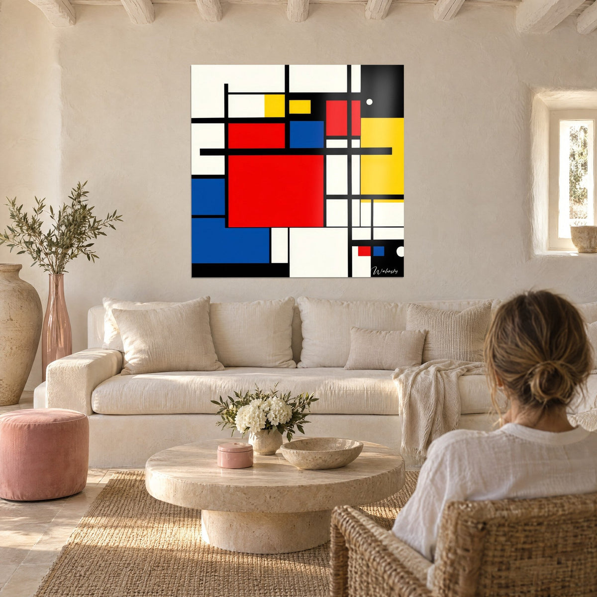 Quadro grande quadrato rosso cerchiato di nero, campiture blu e gialle, coppia di spalle, sopra un divano in un soggiorno luminoso