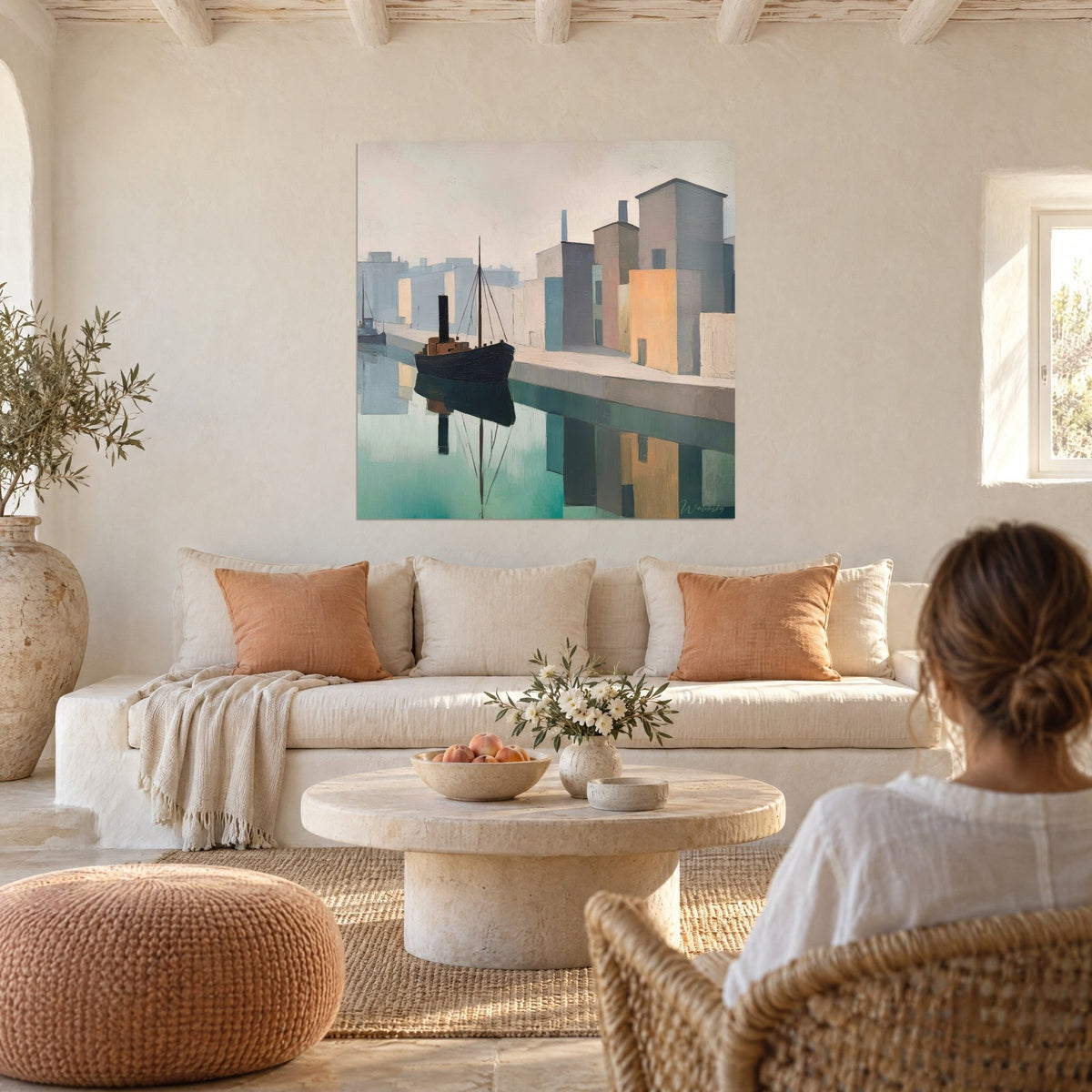 Tableau remorqueur noir à cheminée sur eau turquoise, façades ocre et gris bleu, au-dessus d'un canapé dans un salon lumineux