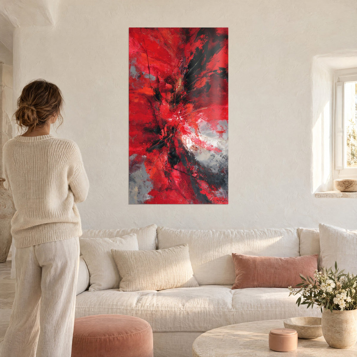 Tableau explosion de rouge vermillon et noir charbon, femme de dos, au-dessus d'un canapé dans un salon lumineux