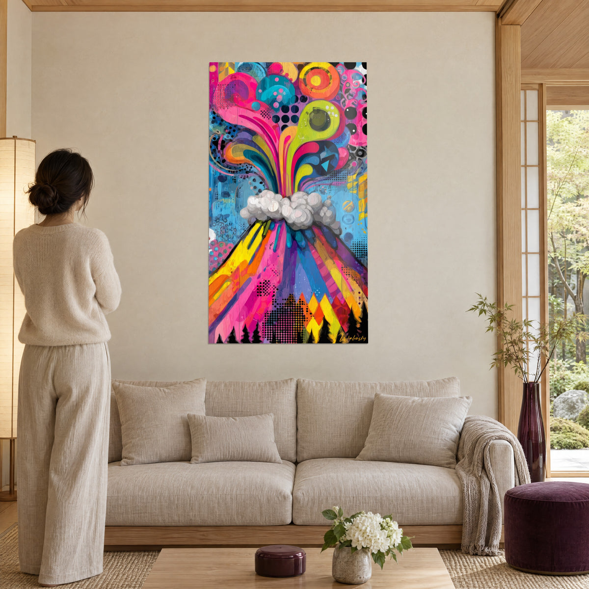 Cuadro volcán pop art en erupción en rosa y amarillo limón, humo gris, fondo azul, sobre un sofá en un salón luminoso