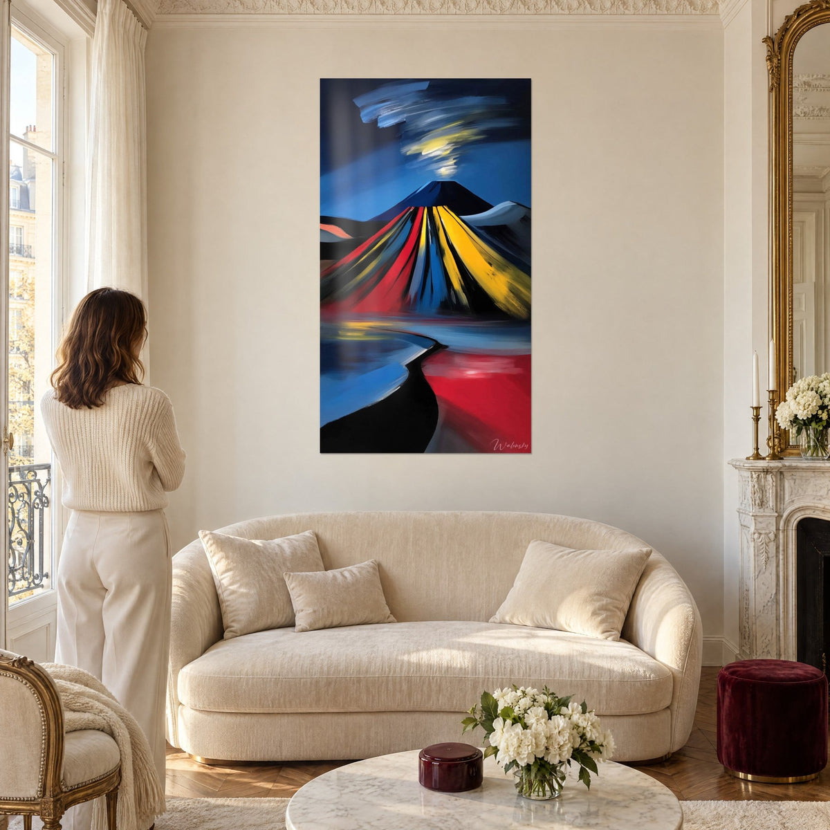 Wall art stylized volcano with red and yellow lava flows against a midnight blue sky, woman seen from behind, above a sofa in a bright living room