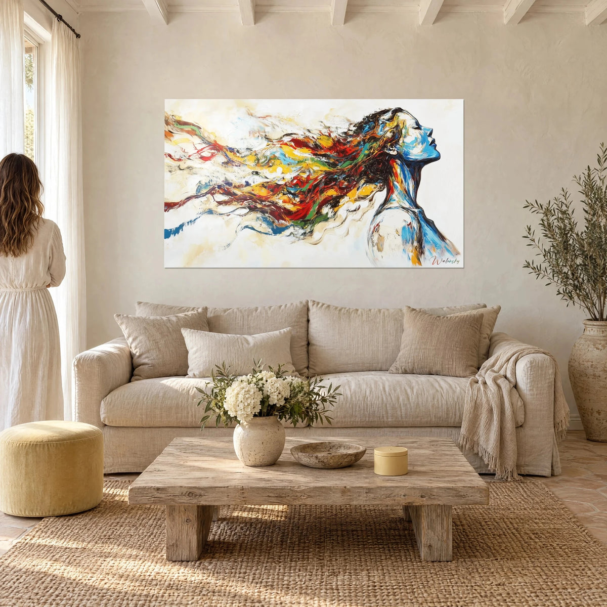 Wall art muse in cobalt blue profile, red and yellow hair flowing against a white background, above a sofa in a bright living room