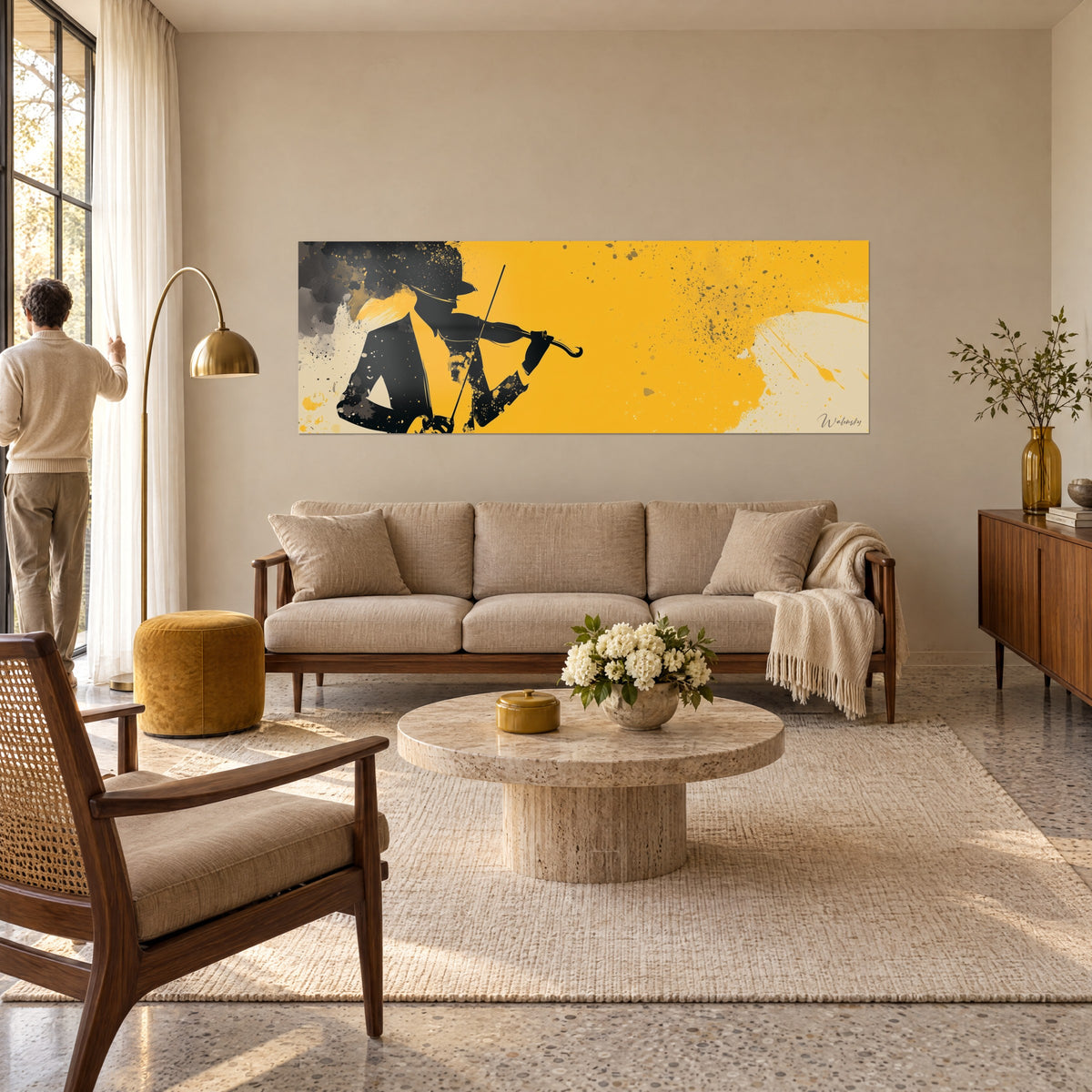 Wall art black silhouette violinist in a hat, bow raised, on a splattered mustard yellow background, above a sofa in a bright living room