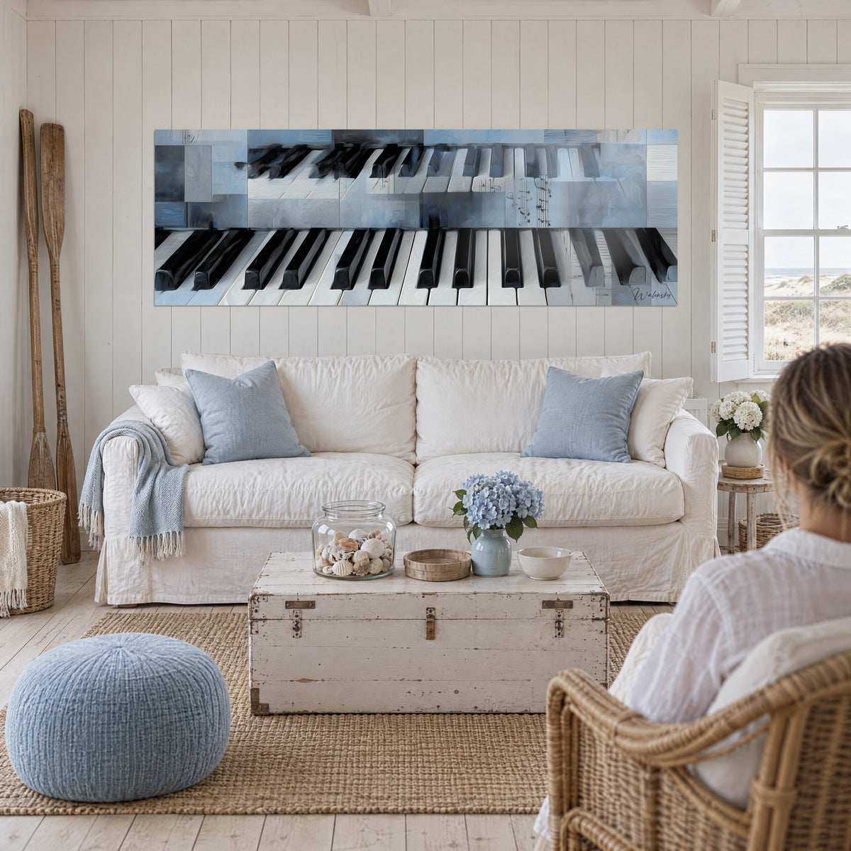 Quadro con tastiera di pianoforte grigio-azzurra, tasti neri e bianchi, note manoscritte, sopra un divano in un soggiorno luminoso