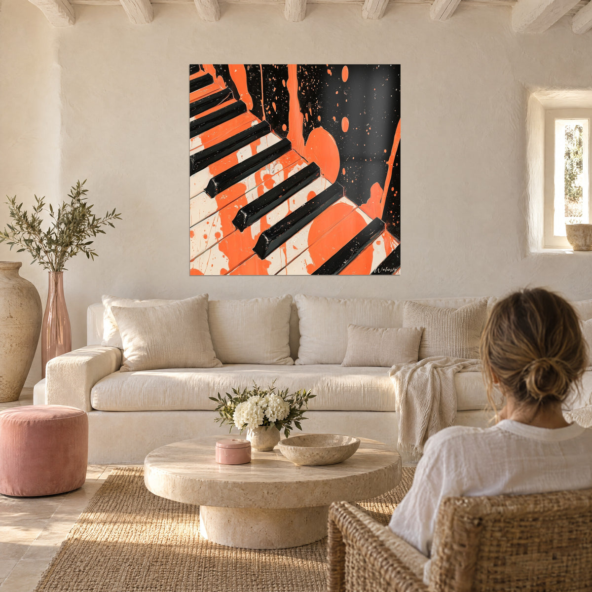 Cuadro teclas de piano en naranja coral y negro, salpicaduras de pintura, dos personas de espaldas sobre un sofá en un salón luminoso