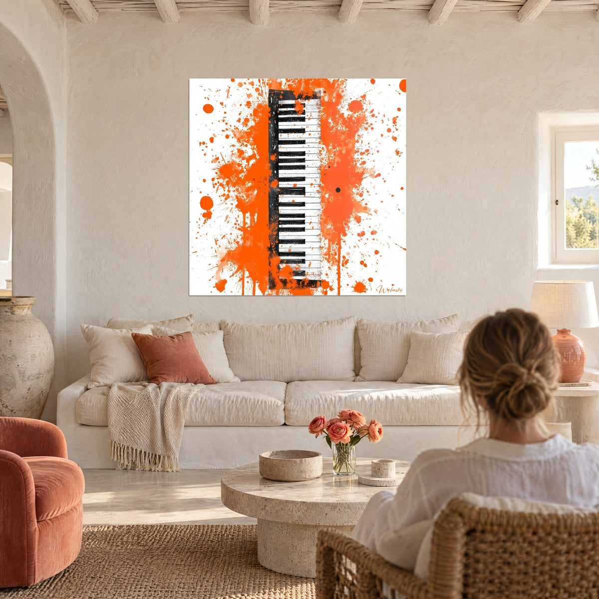 Tableau clavier de piano noir et blanc cerné d'éclaboussures orange vif, femme de dos au-dessus d'un canapé dans un salon lumineux