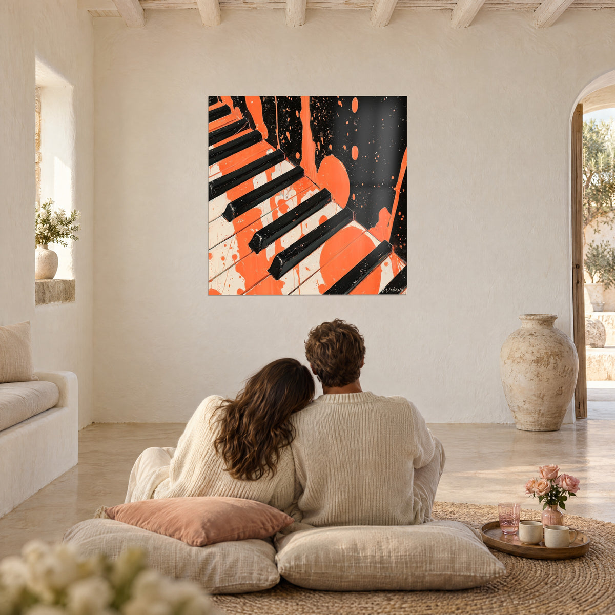 Cuadro piano abstracto negro y naranja pop, pareja abrazada de espaldas sobre cojines rosas y ocres, pared encalada y jarra de barro