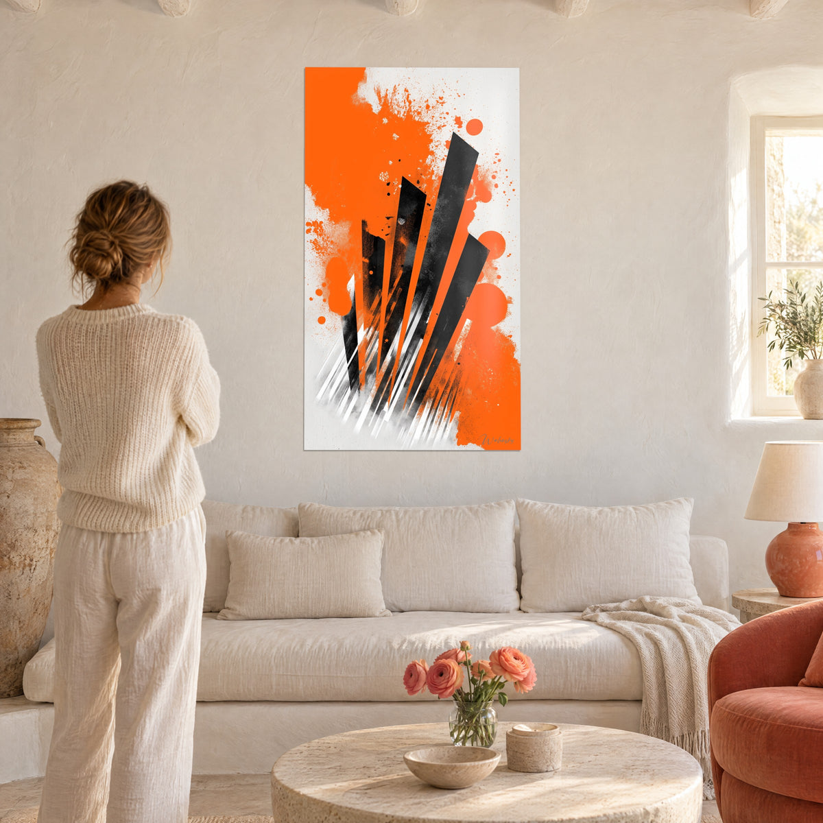 Wall art with black fan-shaped blades over vivid orange splashes, woman seen from behind above a sofa in a bright living room