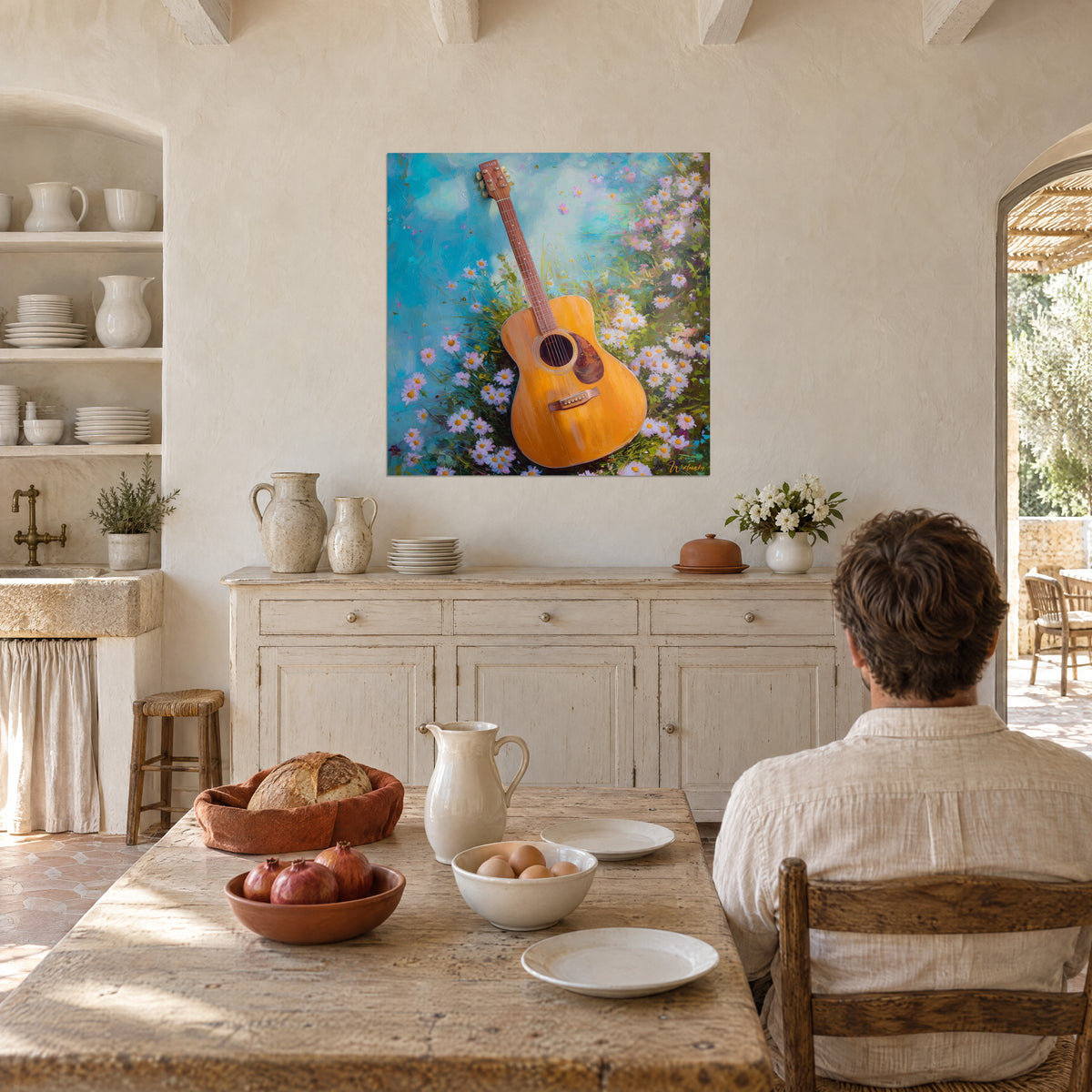 Schilderij Oker akoestische gitaar tussen madeliefjes met gele hartjes, turquoise blauwe lucht, tegenover een man die met zijn rug naar ons toe aan tafel zit in een mas