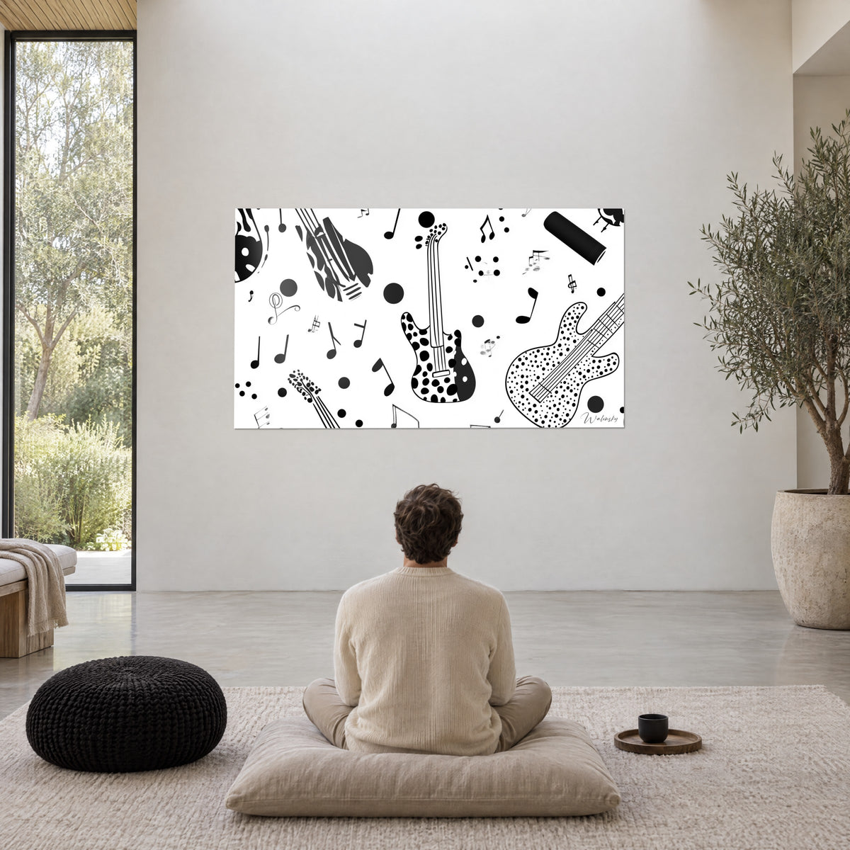 Cuadro de partitura pop art con guitarras negras punteadas sobre blanco, pared crema, puf negro trenzado, olivo en maceta