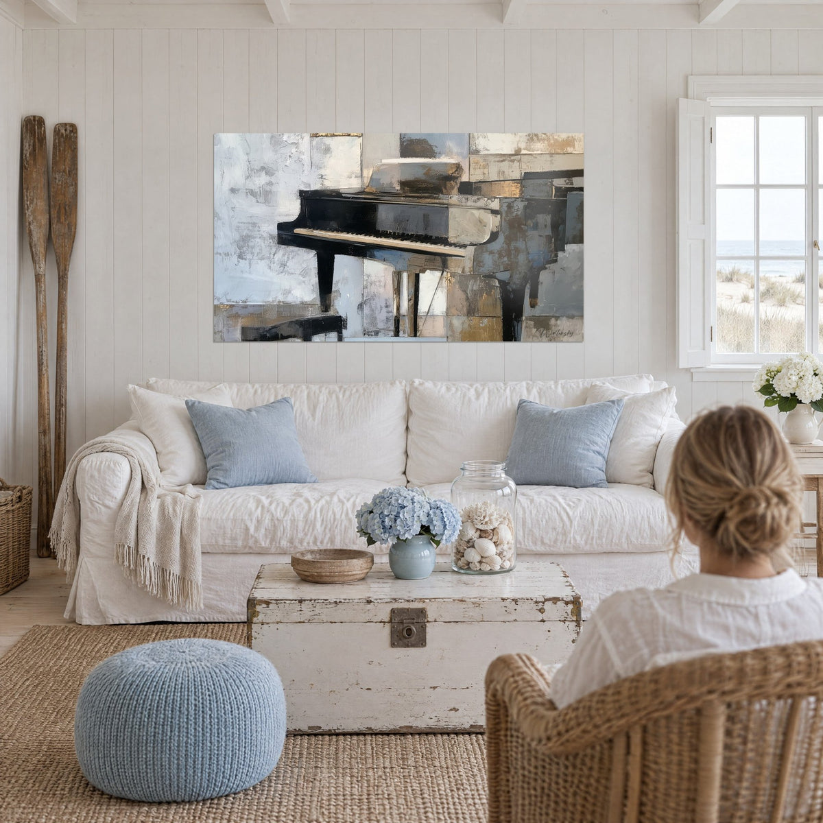 Gemälde Konzertflügel in glänzendem Schwarz zwischen perlgrauen und ockerfarbenen Blöcken, eine Frau von hinten, über einem Sofa in einem hellen Wohnzimmer