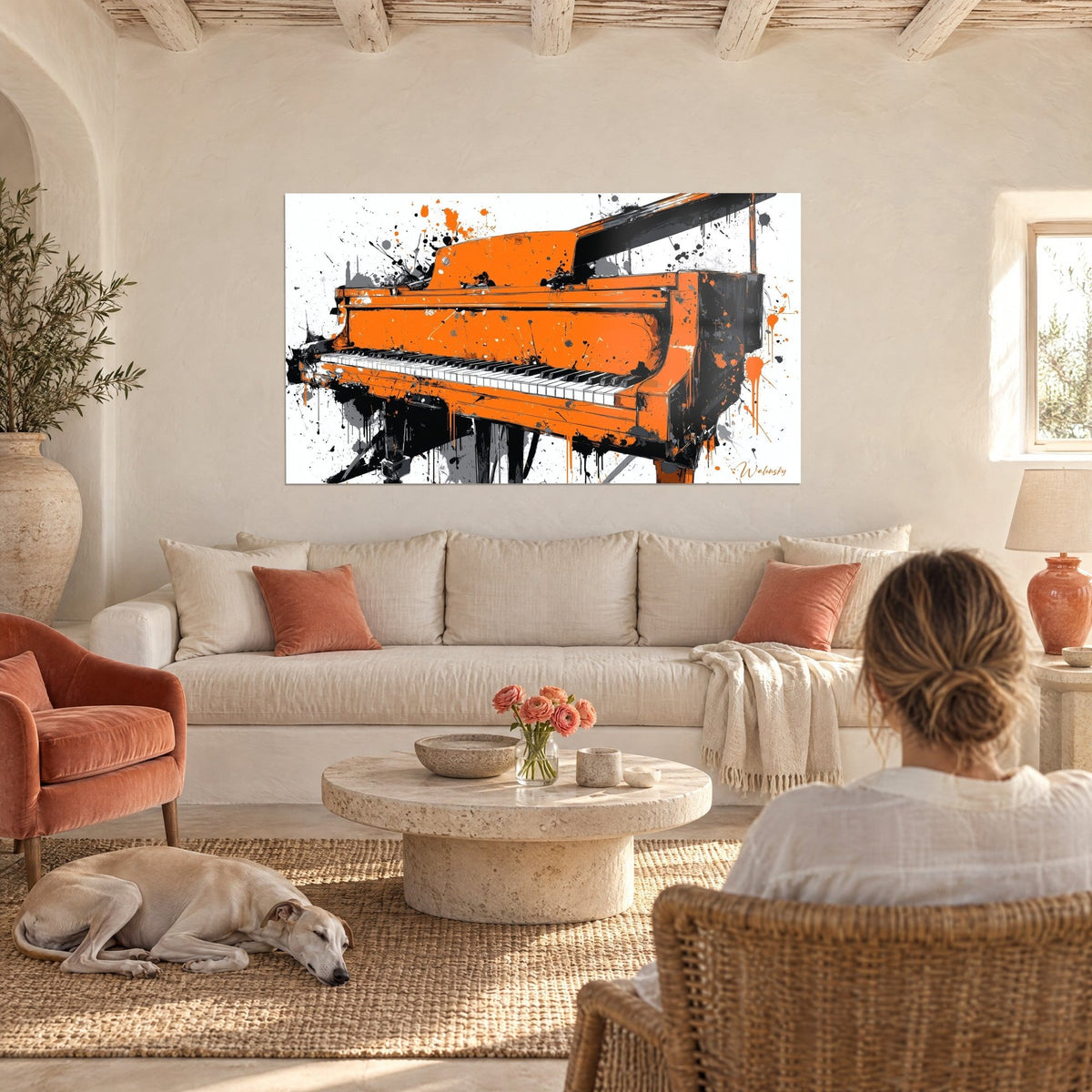 Tableau piano à queue orange éclaboussé de noir sur fond blanc, au-dessus d'un canapé dans un salon lumineux