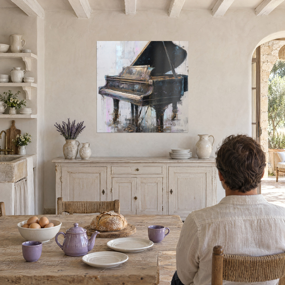 Quadro pianoforte a coda con gambe dorate fluide, nero profondo su bianco sfumato di rosa, di fronte a una persona seduta di spalle al tavolo del mas