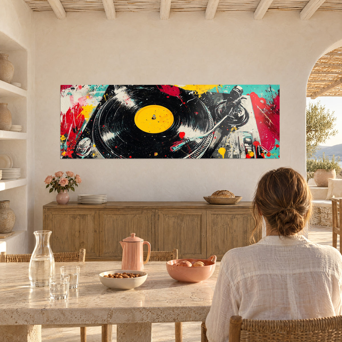 Ζωγραφισμένος πίνακας πικάπ DJ, ασημένιος βραχίονας και κίτρινες σταγόνες σε τυρκουάζ φόντο, γυναίκα από πίσω σε τραπέζι, μεσογειακό σπίτι