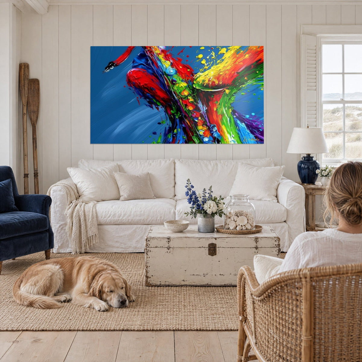 Tableau saxophone en peinture épaisse rouge, jaune et bleu marine, au-dessus d'un canapé dans un salon lumineux