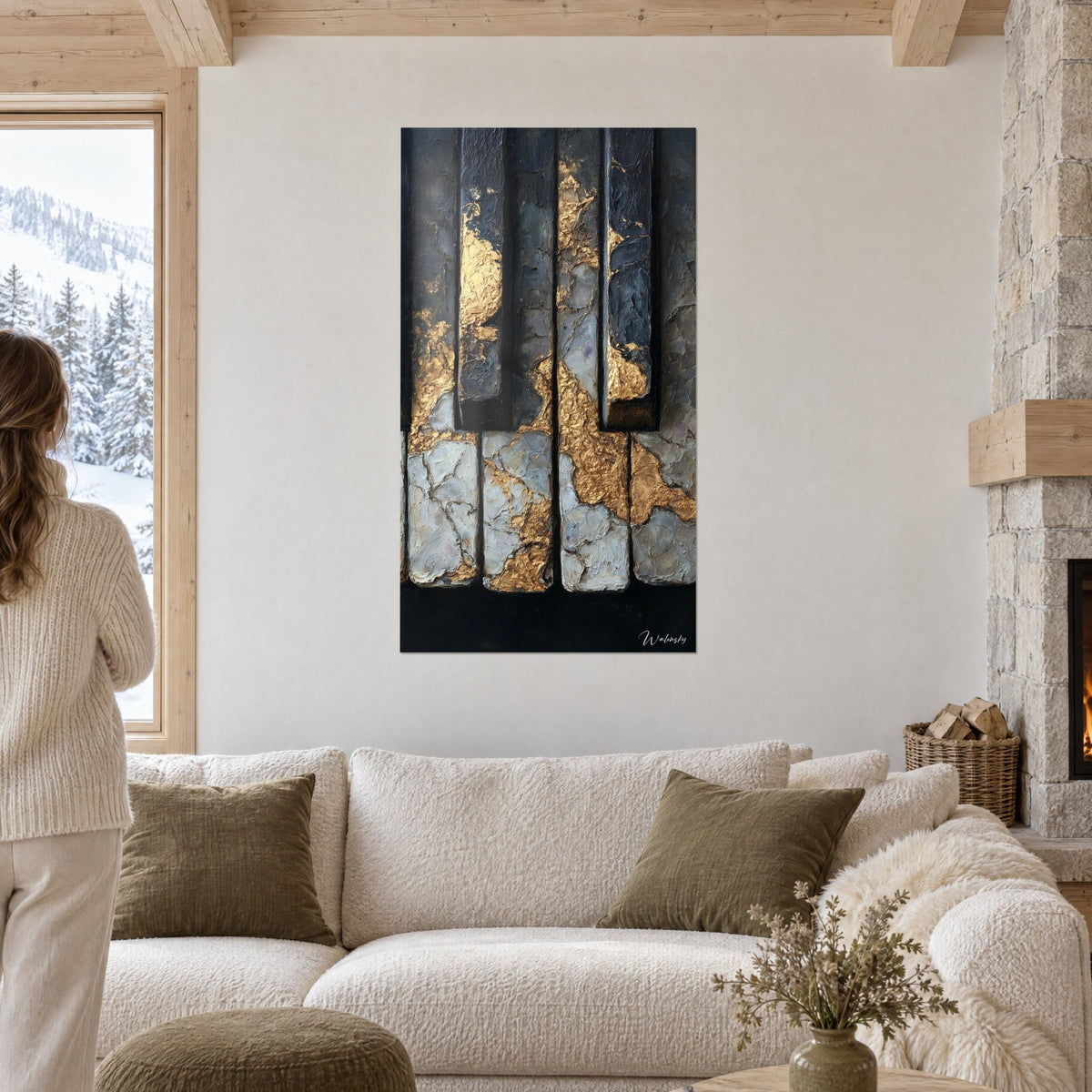 Tableau touches de piano anthracite craquelées veinées d'or, vues par une femme de dos au-dessus d'un canapé dans un salon lumineux