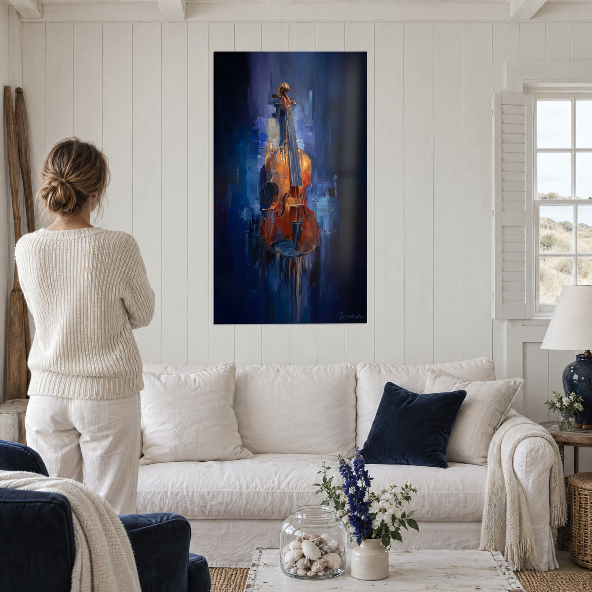 Quadro violino ambra su fondo blu navy, tocchi di spatola, visto di spalle da una donna sopra un divano in un soggiorno luminoso