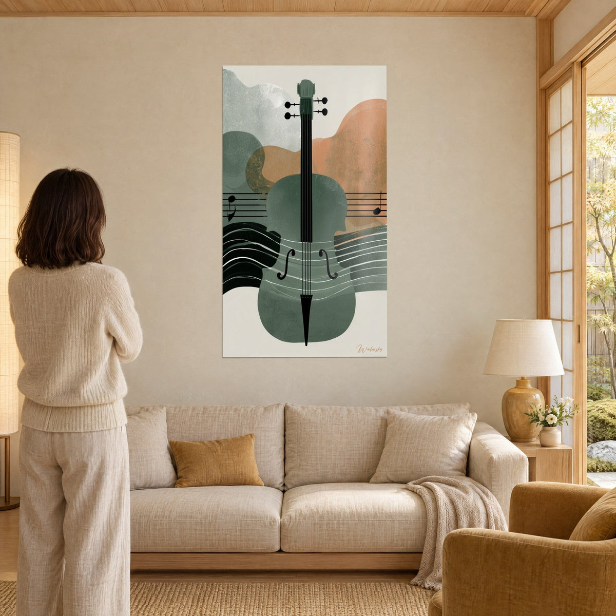 Cuadro violonchelo estilizado en verde salvia y naranja, pentagrama negro ondulado, mujer de espaldas, encima de un sofá en un salón luminoso