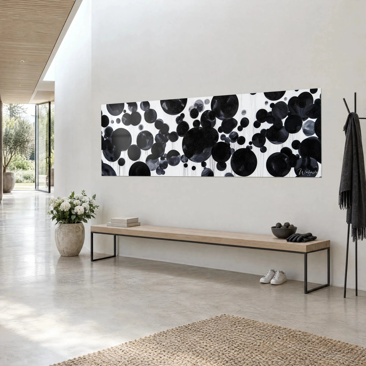 Wall art of dark bubbles in varied sizes, slate grey and deep black on flowing white, light wall of an architect's house