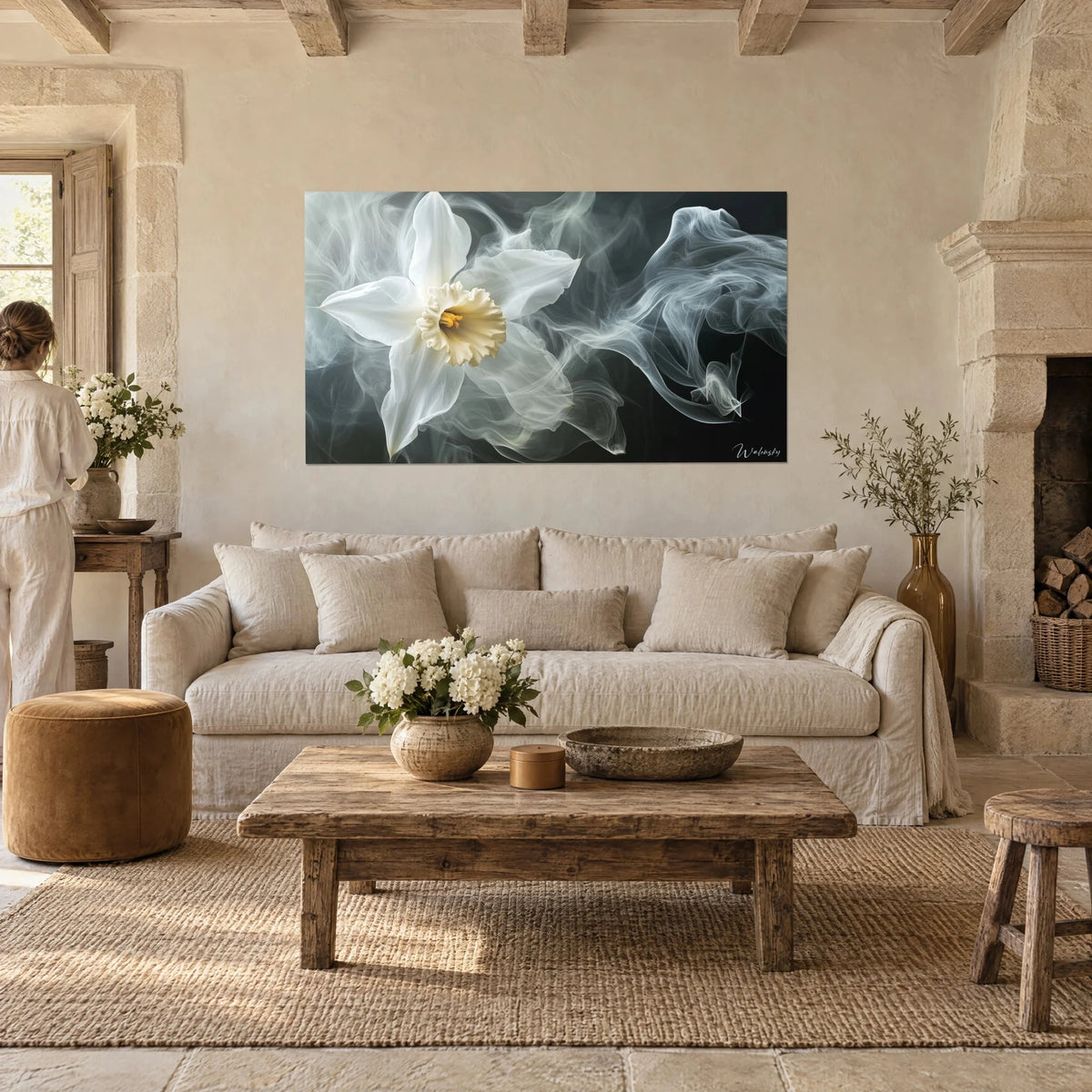 Wall art white daffodil with a pale yellow heart, grey smoke veils on a black background, a woman seen from behind, above a sofa in a bright living room